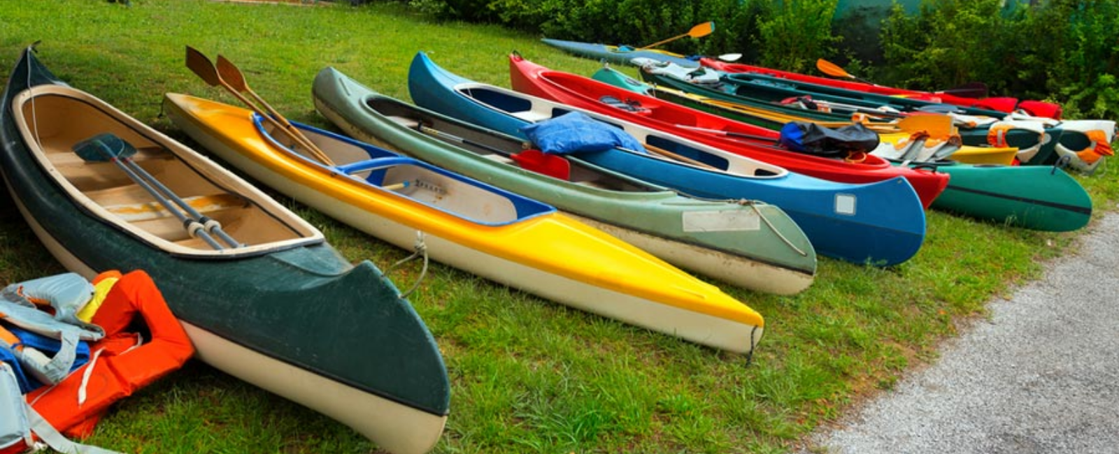 Kayaks and canoes on the grass by a lake